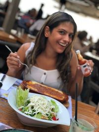 Portrait of a smiling young woman having food in restaurant