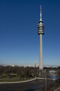 Communications tower in city against clear blue sky