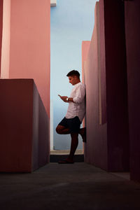 Young man absorbed in his mobile phone between colorful walls