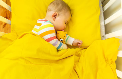 High angle view of baby girl sleeping in crib at home