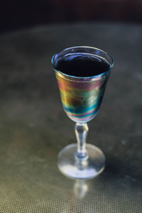 Iridescent black lemonade cocktail drink on gold brass table evening