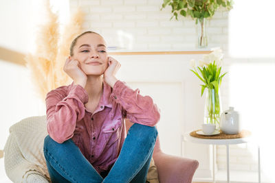 Smiling caucasian millennial girl sitting resting in chair in casual clothes