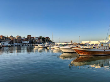 Boats moored in harbor against buildings in city