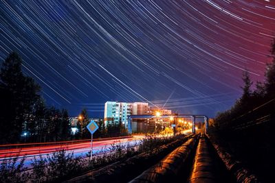 Illuminated railroad tracks against sky at night