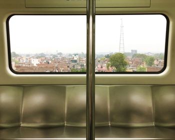 Close-up of cityscape against sky seen through train window