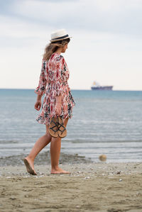 Woman standing at beach against sky