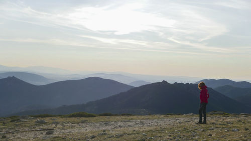 Rear view of woman standing on mountain against sky