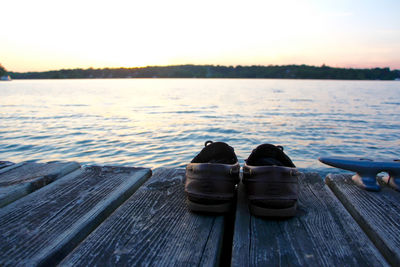 Pier on lake against sky during sunset