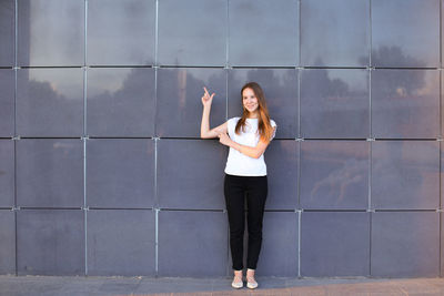 Full length of woman standing against wall