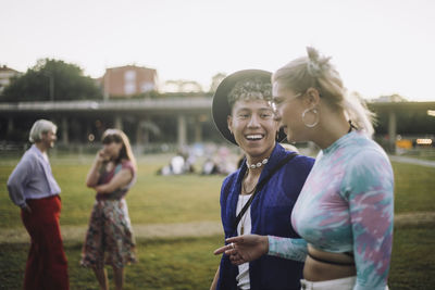 Happy young man talking with female friend while walking at park