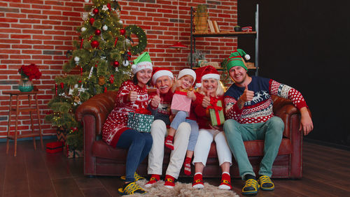 Cheerful family sitting on sofa against christmas tree at home