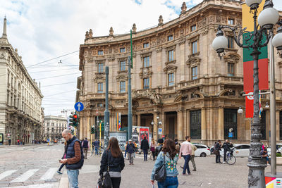 People walking on street against buildings in city