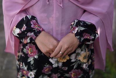 Midsection of woman with hands clasped wearing hijab dress