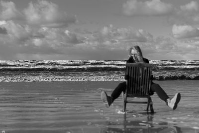 Rear view of woman on beach against sky