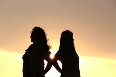 Silhouette couple against sky during sunset