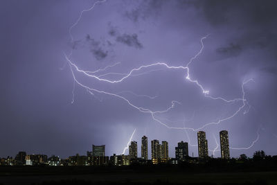 Lightning over illuminated buildings in city at night