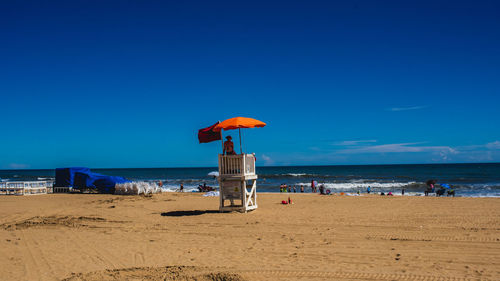 Lifeguard hut on beach against blue sky