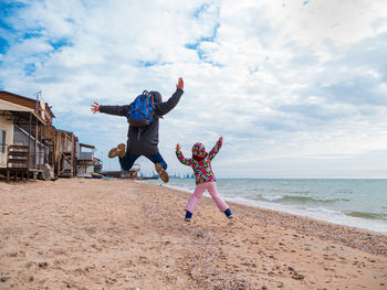 Father daughter jumping flying on a beach.lifestyle photo real people happy active family having fun