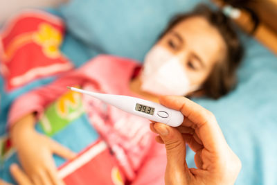 Cropped hand of mother holding thermometer examining patient