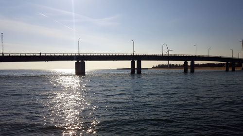 Bridge over calm sea against sky