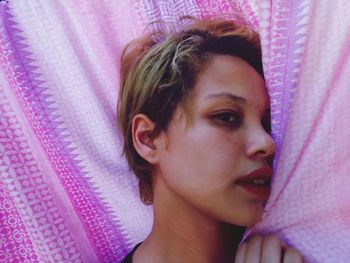 High angle portrait of young woman lying on bed