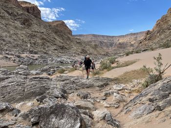 Rear view of man walking on rocks against mountains