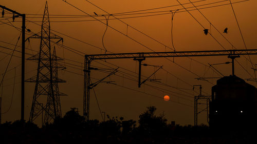 Low angle view of silhouette electricity pylon against sky during sunset