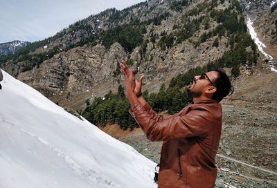 Young man standing on snow covered mountain