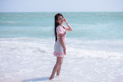 Full length of young woman standing on beach