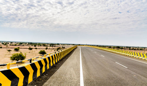 Road leading towards highway against sky