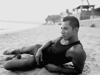 Portrait of shirtless man sitting on beach