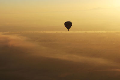Silhouette hot air balloon flying against sky during sunset