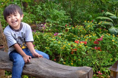 Portrait of smiling boy sitting on plants