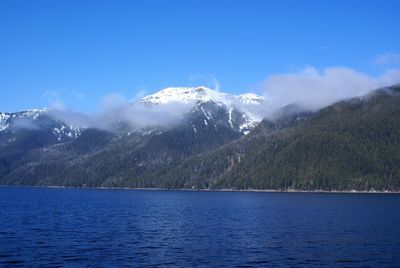 Scenic view of lake by mountains against blue sky