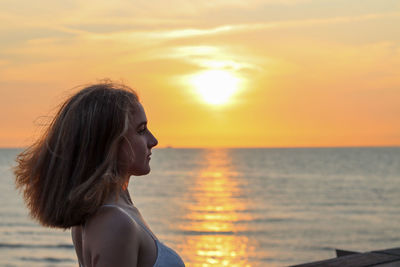 Portrait of young woman looking at sea during sunset