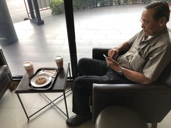 Midsection of man using mobile phone while sitting on table