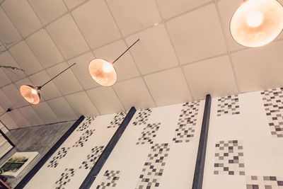 Low angle view of illuminated pendant lights hanging on ceiling