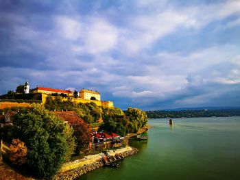 Buildings by river against sky