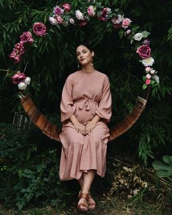 Portrait of pregnant woman standing on flowering plants