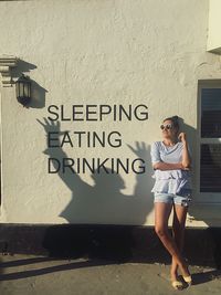 Full length of young woman standing against wall