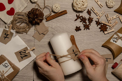 Cropped hand of woman holding christmas decorations on table