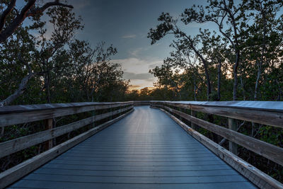 Footbridge amidst trees against sky