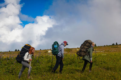 Hiking women and men with backpack enjoying the trekking, go to the mountains, in the background