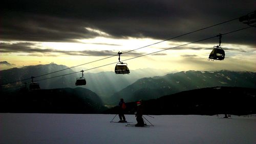 Overhead cable car on mountain against cloudy sky