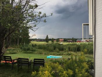 Park bench by buildings against sky