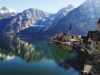 Scenic view of lake by buildings and mountains against sky