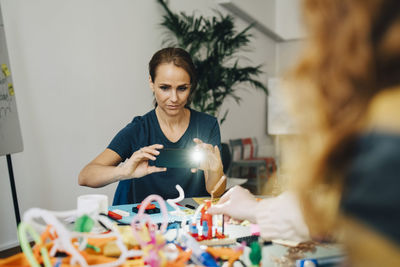 Confident businesswoman photographing stationery on table at creative office