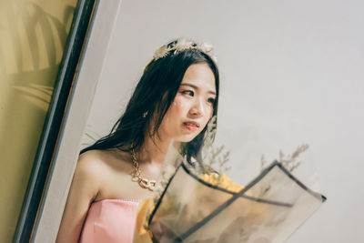 Reflection of young woman with bouquet seen in mirror