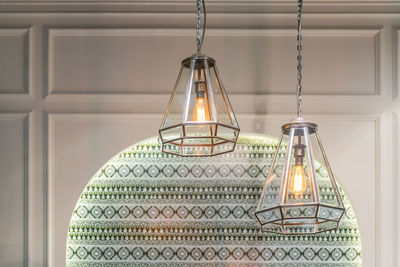 Close-up of illuminated pendant lights hanging on wall at home