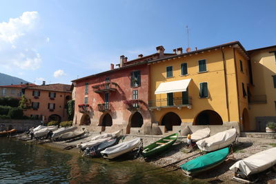 Boats moored on river by buildings in city against sky